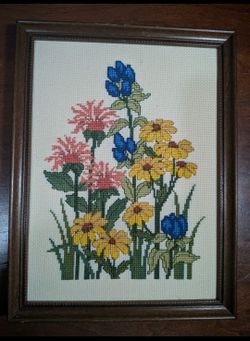 Framed cross-stitch or needlepoint wall art piece featuring a bouquet of wildflowers