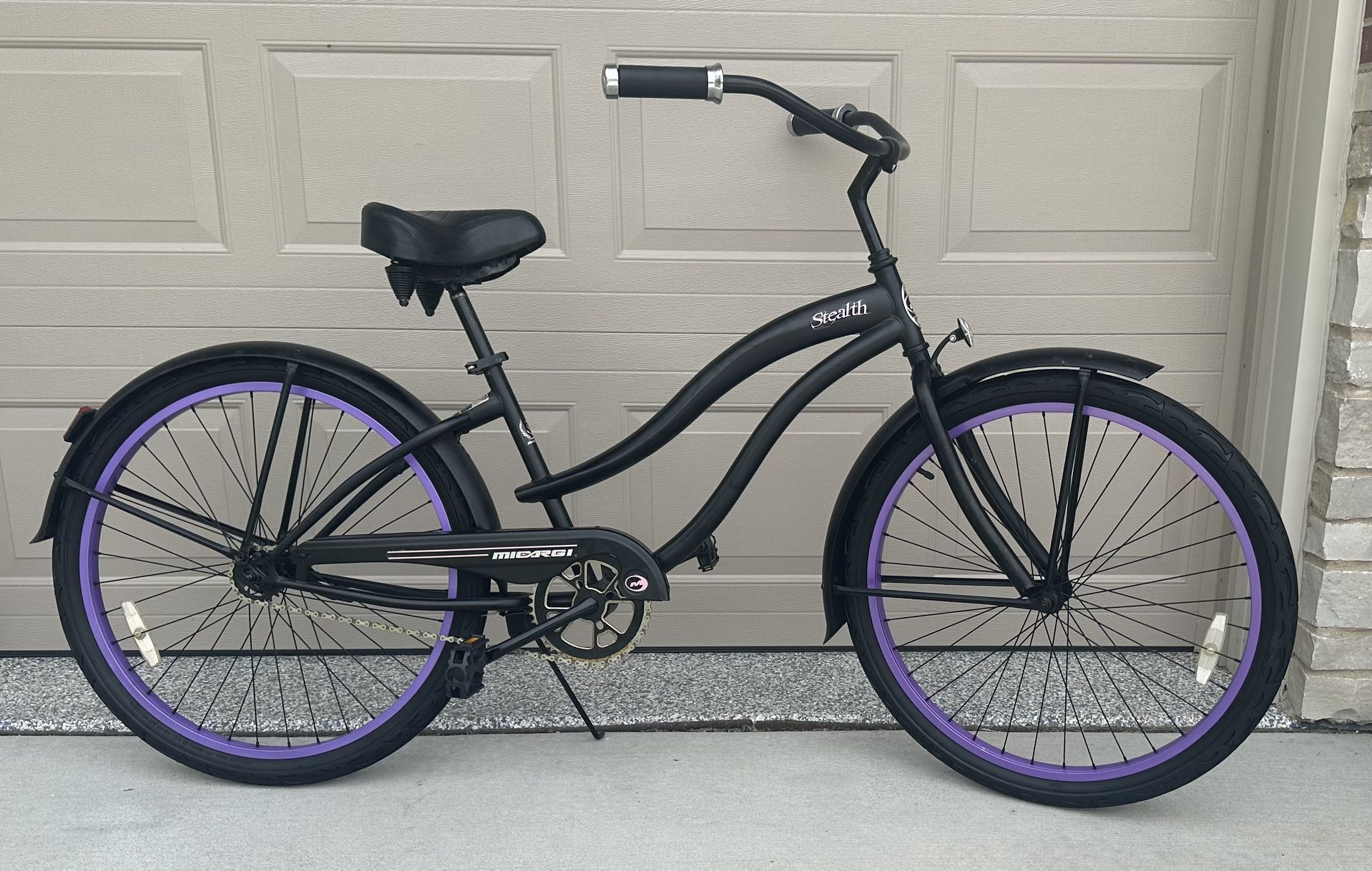 Beautiful Micargi Stealth 26-inch cruiser bicycle with a black frame and distinctive purple rims.