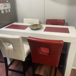 White Formica kitchen or dining room table with four chairs, two white, two red, the leader chairs, the table measures 57 inches long, 23 1/2 inches w
