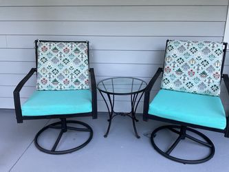 Black wrought iron swivel rocking chairs with cushions and table