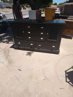 Real wood black seven drawer dresser with two storage compartments on each side behind the doors