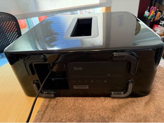 Powerful Sonos Sub (Gen 3) S26 is a wireless subwoofer with a glossy black finish. It has a dual-driver design and a central acoustic port. This unit 