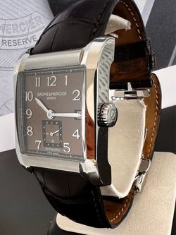 Baume & Mercier Geneve automatic watch with a rectangular stainless steel case, brown dial, Arabic numerals, small seconds subdial, and a dark brown c