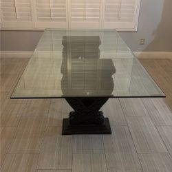 Neoclassical-style Dining Table with a clear glass top and a highly ornamental, black carved base