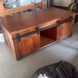 Farmhouse-style wood coffee table with sliding barn doors and storage.