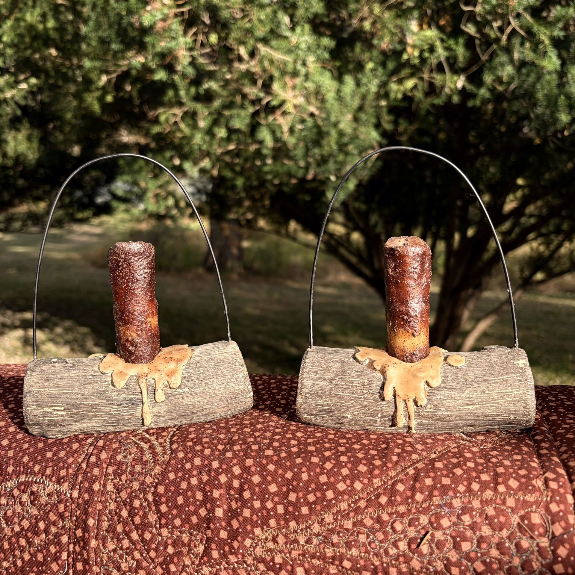 primitive-style, battery-operated LED candle on an imitation log base with a wire hanger
