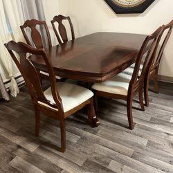 A dining room set made of solid wood. A large table, 6 chairs, a sideboard, and a chest of drawers.