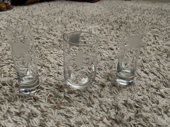 clear glass pieces featuring frosted etched designs, consisting of two tall shot/juice glasses and one shorter rounded tumbler. Princess house