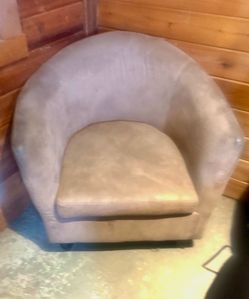 Upholstered tan barrel chair  with a microsuede-like fabric.