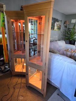 Pair of light wood corner cabinets with top and bottom lights and mirrored backs
