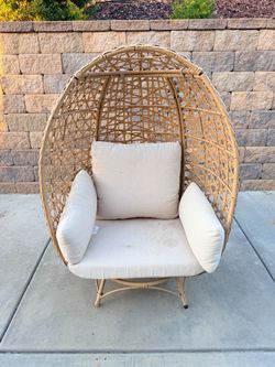 Comfortable wicker egg chair with a cushion, perfect for outdoor relaxation.