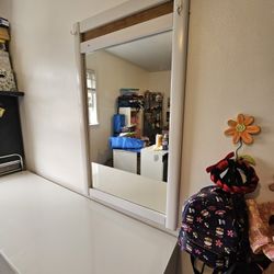 White chest of drawers with a mirror and a protective glass top.