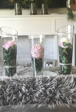Three clear vases with leaves and flower