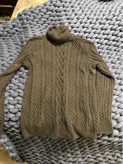 Textured cable-knit turtleneck in a muted olive tone.