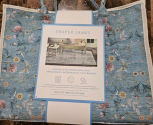 Draper James indoor/outdoor area rug, measuring 5 ft x 7 ft- floral design in light blue- comes in a tote.