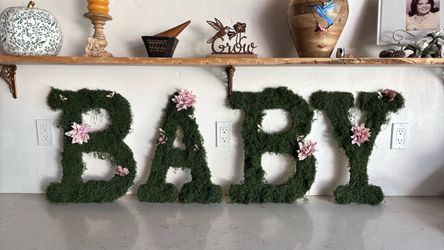“BABY” wood letters covered in moss