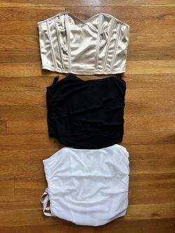 Set of three tops in satin and cotton. Includes a gold satin corset, a black corset and a white corset. Perfect for versatile styling. $20