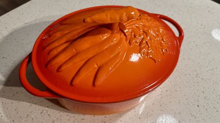 Technique enameled oval cast iron dutch oven with lid. Red Orange in color with carrot handle and lid. In very good condition. A few chips in the enam