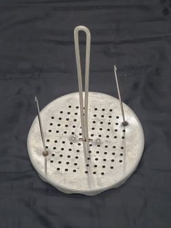 perforated aluminum turkey fryer rack and vertical stand, commonly used for deep-frying poultry in outdoor cookers