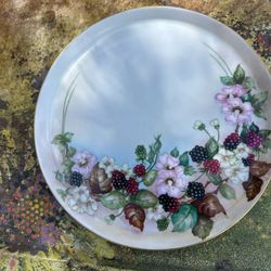 This is a hand-painted porcelain decorative plate with a floral and berry design.