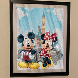 Disney Mickey Mouse and Minnie Mouse art piece on black frame infron of castle