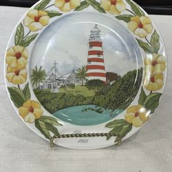 A decorative collector plate by Elyse Wasile depicting a Bahamian lighthouse scene from 1985. 8”