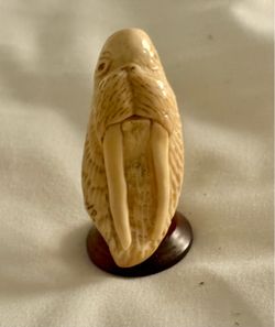 Walrus face carving. Sits on wooden base. 2”x1”