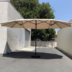 $130 (Brand New) Large 15 ft double sided outdoor umbrella with 65 lbs plastic weight base (beige color)