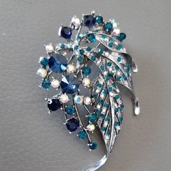 Silver tone brooch with green and blue stones.