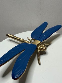 A decorative dragonfly figurine with a golden body and blue wings.