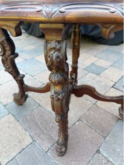 Vintage accent table with decorative carved wood base and marble-look oval top.