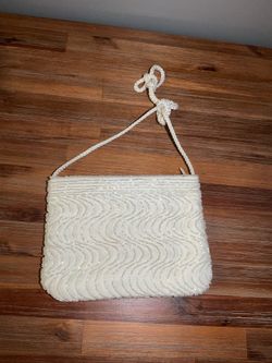 This vintage Carla Marchi evening bag features a wavy design with white beads and an adjustable drawstring strap.