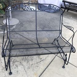 A beautiful wrought iron garden glider bench 