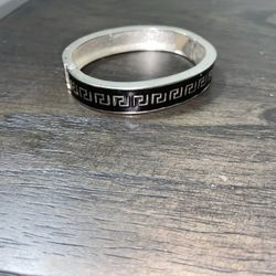This is a sterling silver hinged bangle bracelet with a black Greek key pattern. 