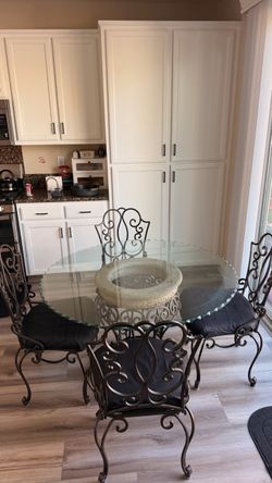 48” round glass dining table set with 4 matching wrought iron chairs.