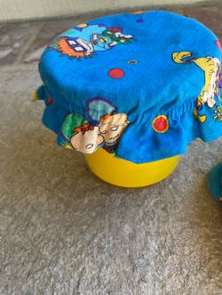 Two yellow containers with fabric lids with pop frog plastic toys