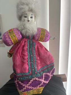 Russian porcelain doll features a traditional costume, including a fur-trimmed hat and an ornate, pink embroidered dress