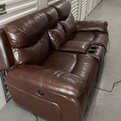 Double recliner leather chairs with two cup holders and a open console 