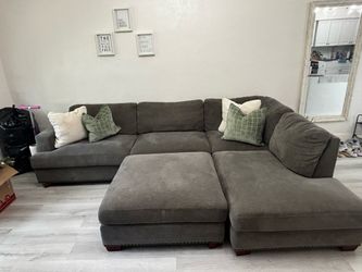 Sofá seccional gris en forma de L con reposapiés