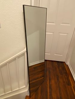 Full-Length Mirror Features a Sleek Black Frame and a Tall, Minimalist Leaning Design.