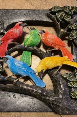 Stunning three-dimensional wall art features a flock of vividly painted birds perched on carved branches within a textured dark frame.