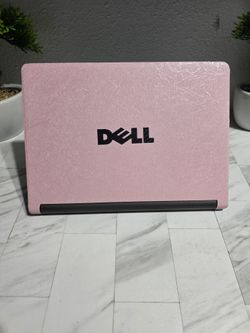 Pink Dell Chromebook has a textured pink skin on the outer lid. The device is black with a standard QWERTY keyboard and integrated touchpad. Great bat