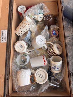 Crate full of retired Starbucks cups mugs and NFL glasses