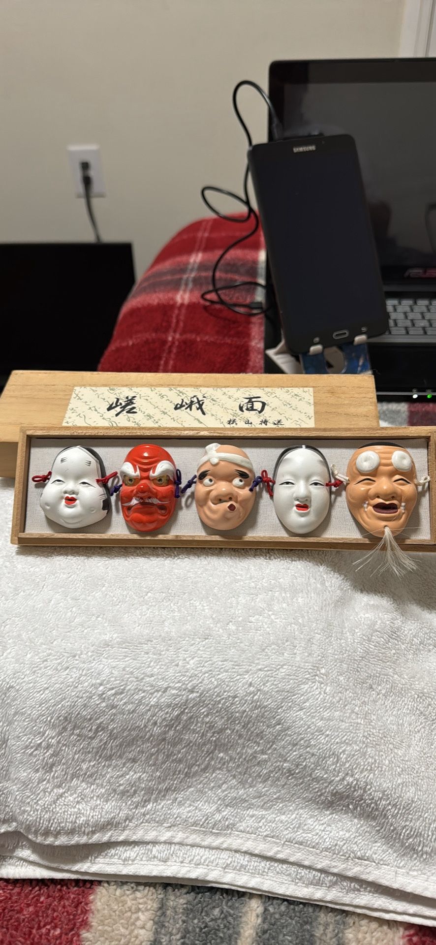 a set of five miniature Japanese Noh masks displayed in a wooden box