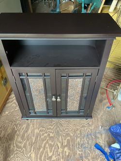 Dark Brown Storage Cabinet with Glass Doors it’s 34 inches tall 27 wide and 12 inches deep