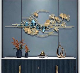 New in its box Elegant metal wall sculpture is gold with blue and white mountain accents. This piece has a ginkgo leaf design integrated with a circul