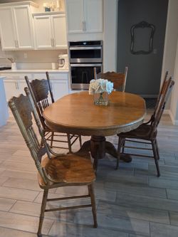 Solid Oak Dining Set with a pedestal base table with 4 chairs. Used, in good condition. Normal Wear! 2 of the chairs are missing wood spindles.