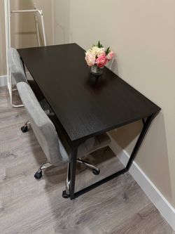 Modern black desk with 2 gray office chairs.