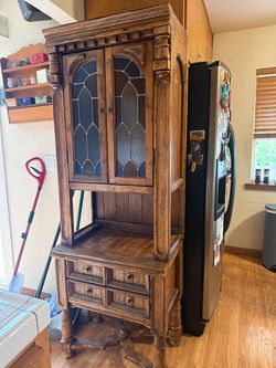 vintage wooden china cabinet and hutch with textured amber and blue stained glass doors and carved pillar details