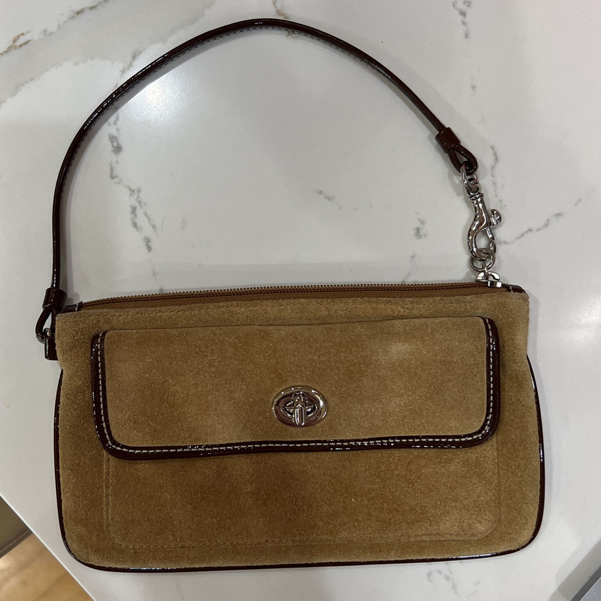 Brown suede wristlet with brown patent leather trim  turn lock pocket. Coach
